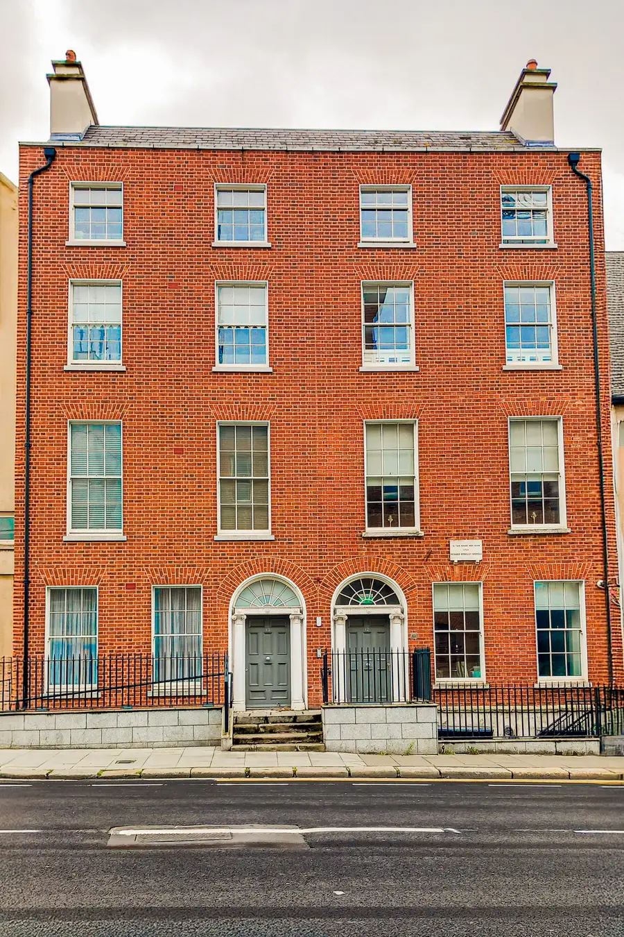 A red-brick Georgian building in Dublin with white sash windows and two panelled doorways