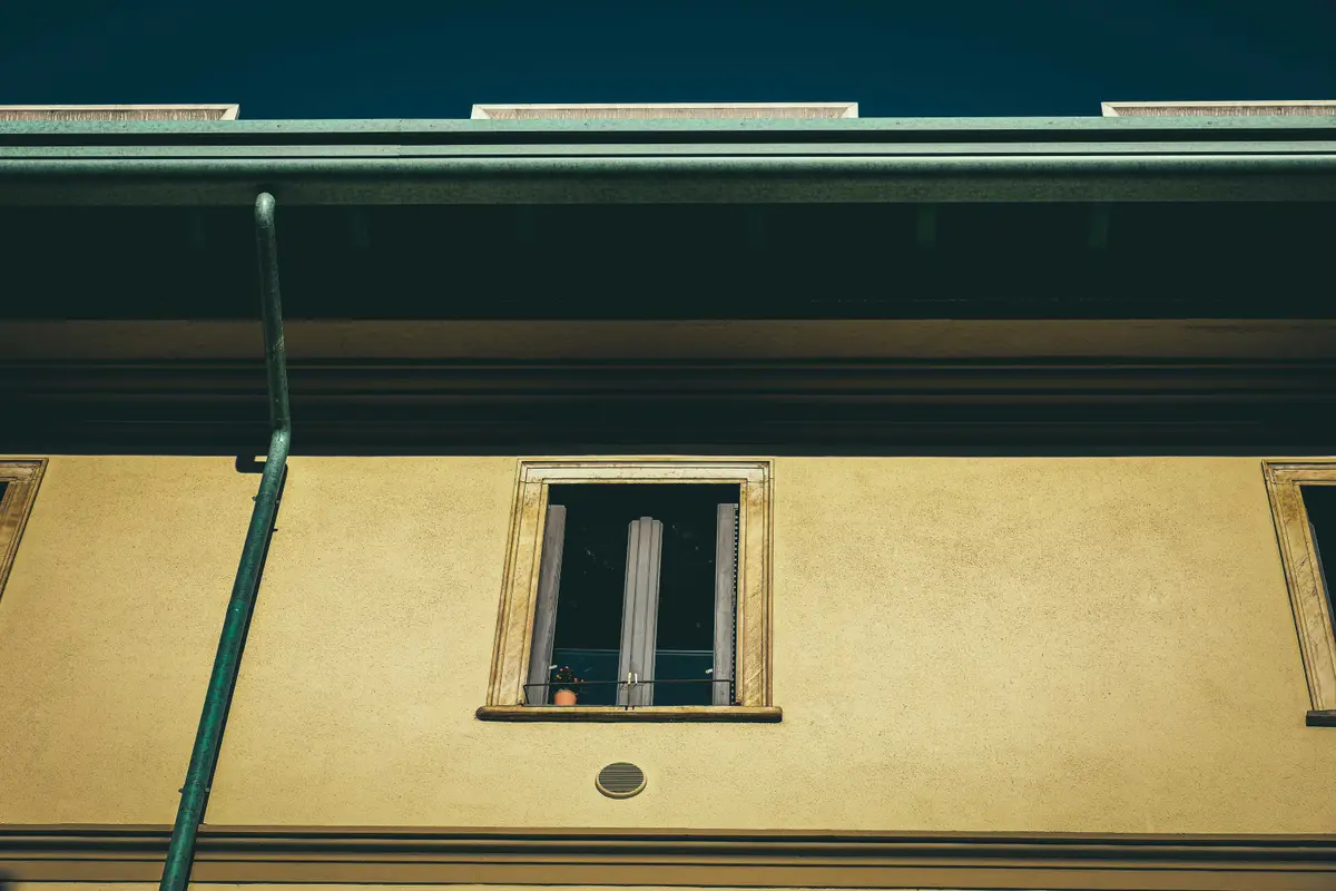A rendered house wall with a single downpipe running down it