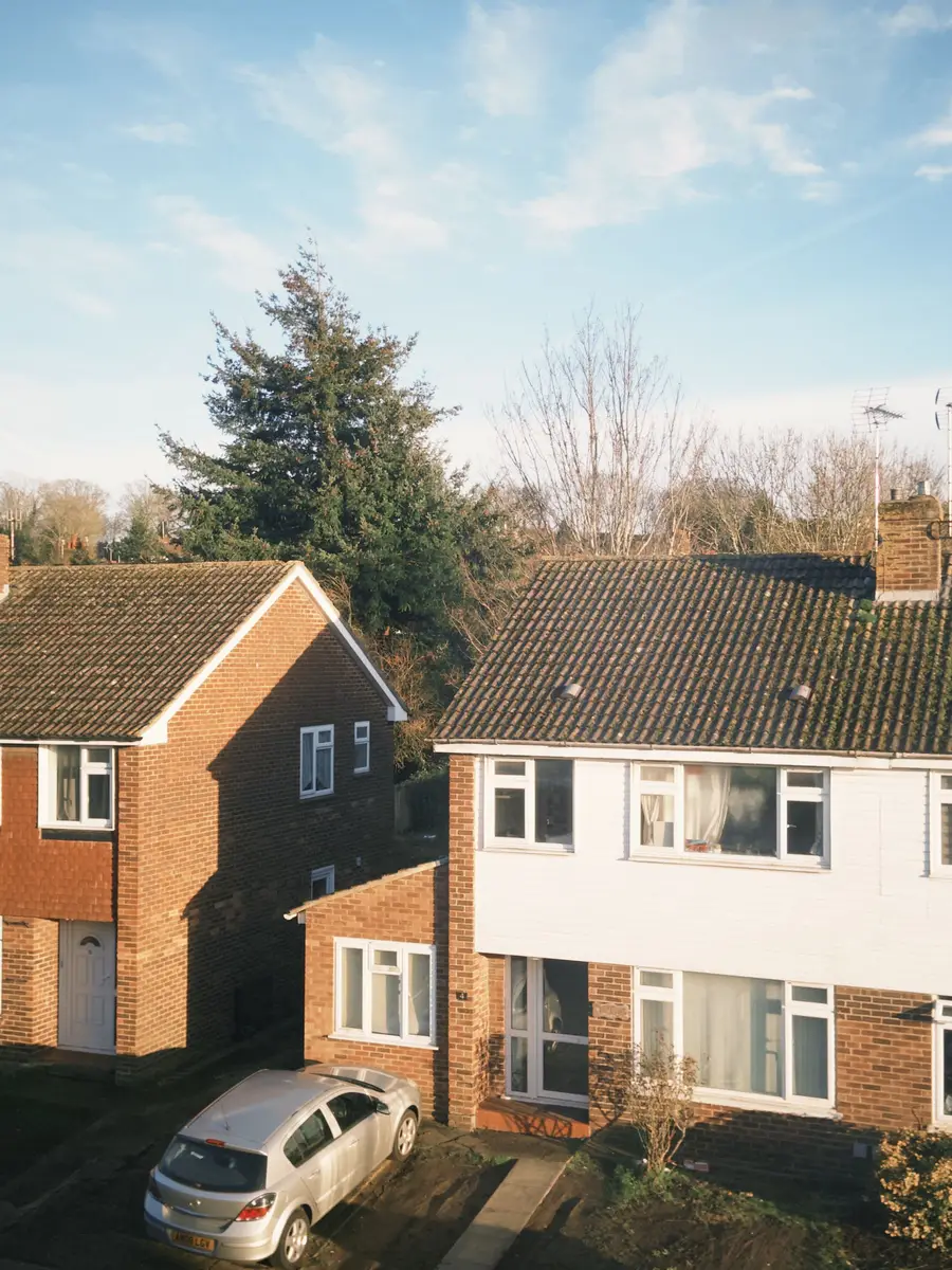 Two-storey semi-detached house with a dark concrete-tiled roof in low evening sun