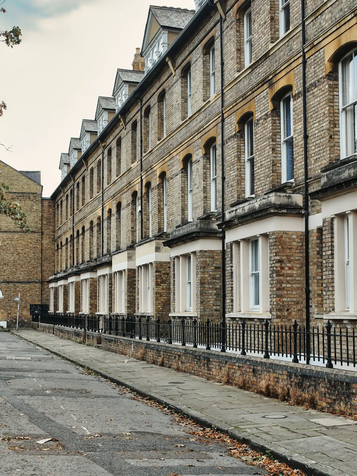 A row of Victorian terraced houses with iron railings along a narrow street