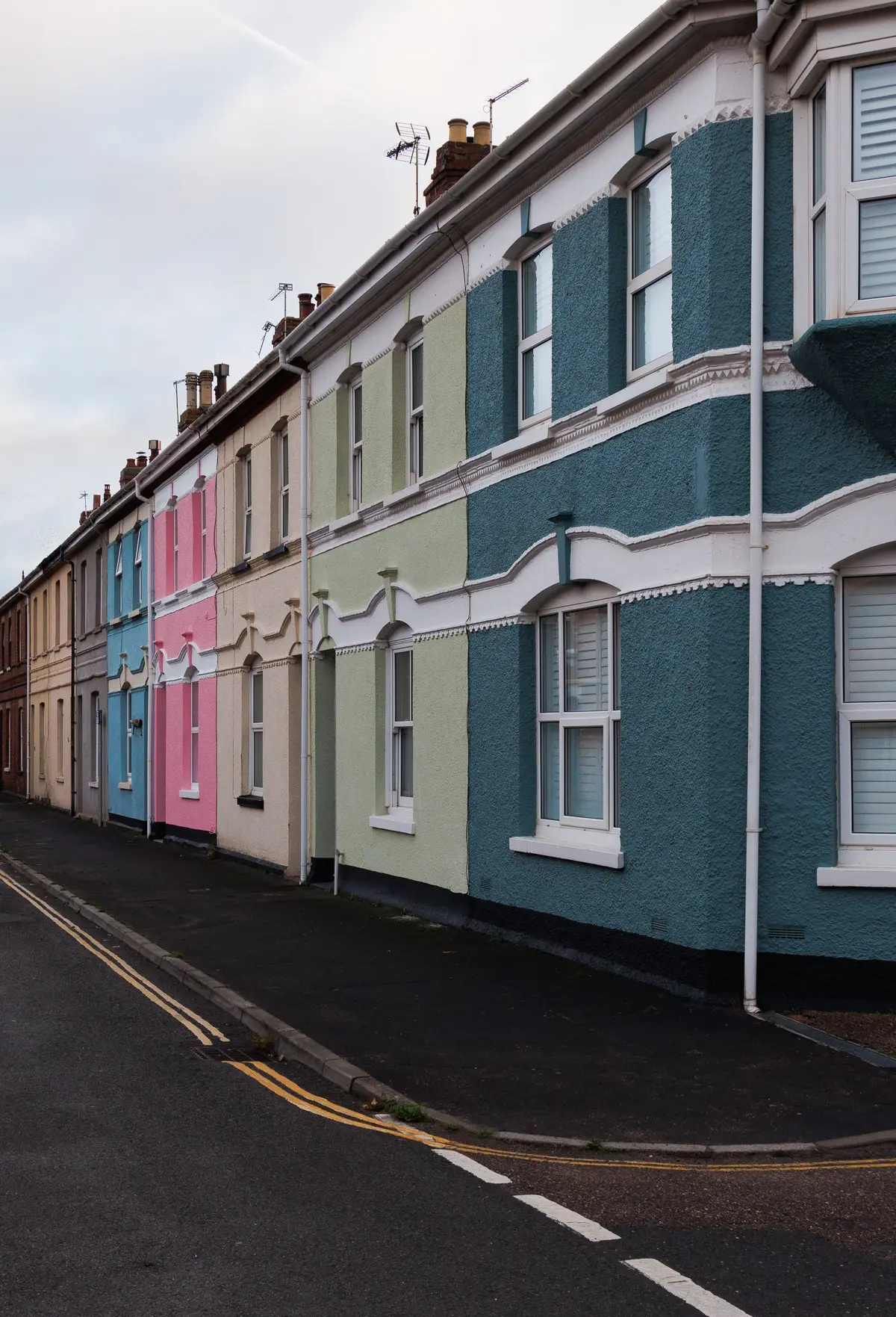 A row of colourfully rendered and painted terraced houses on a narrow street