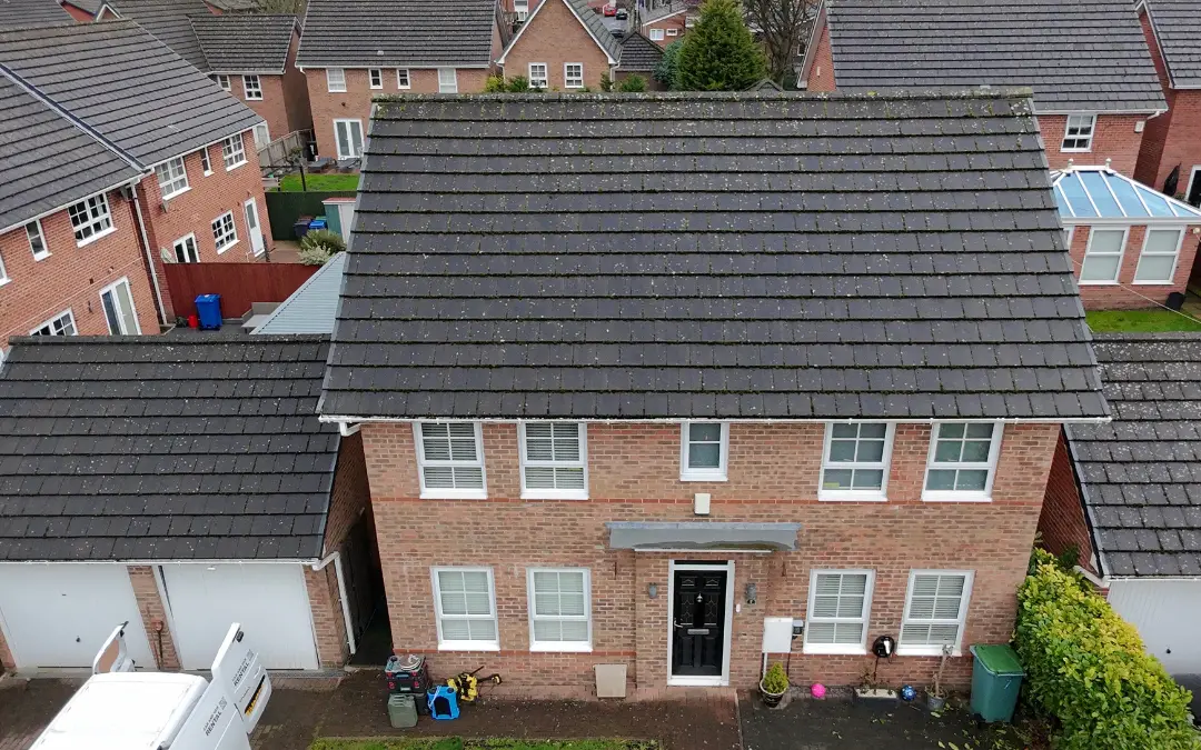 A house elevation with green growth and staining below the gutter